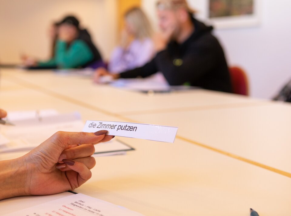 Participants in a language class holding a task card.