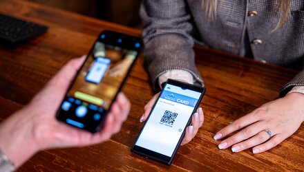 Eine Person scannt einen QR-Code auf einem Smartphone zur Bezahlung.