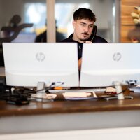 Ein Mitarbeiter spricht am Telefon an einem Schreibtisch mit zwei Monitoren.