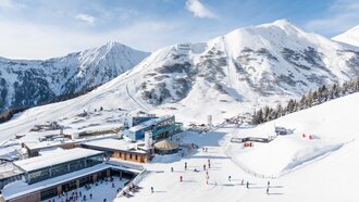 Sneeuwbedekte bergen en skiërs in een skigebied.