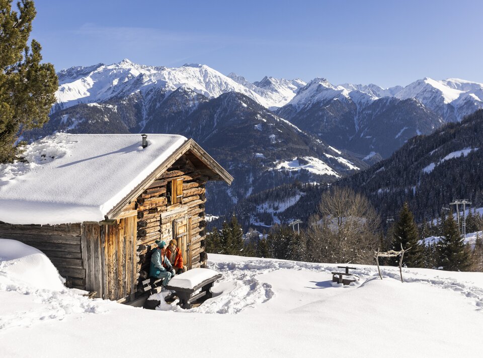 Cozy cabin in the snow with stunning mountain backdrop.