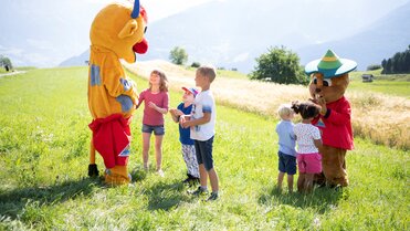 Fröhliche Kinder interagieren mit Maskottchen in der Natur.