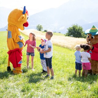 Happy children interact with mascots in nature.
