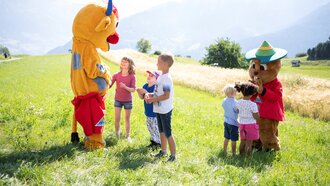Fröhliche Kinder interagieren mit Maskottchen in der Natur.