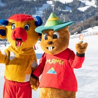 Two cheerful mascots on a ski trail in winter.