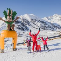 Happy kids and a ski instructor pose in front of a large snow bunny.