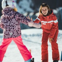 A ski instructor is teaching a child how to ski in the snow.