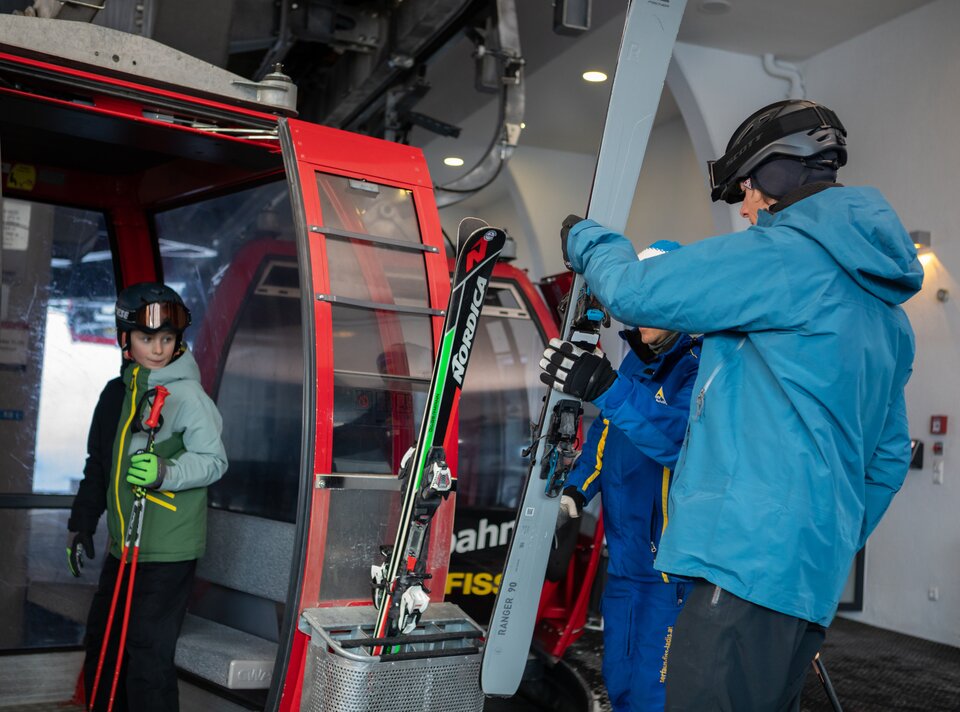 Family boards a gondola at the ski lift, ready for skiing.