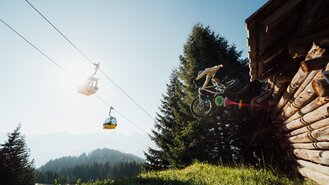 Ein Mountainbiker spritzt während eines Sprungs vor einer Lodge.