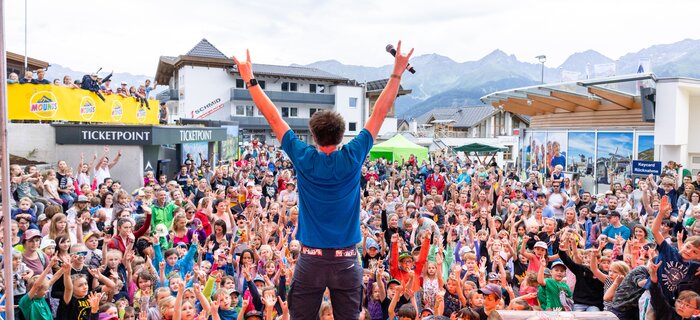 A performer engages a large crowd at an event.