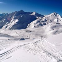 Weite Sicht auf schneebedeckte Gipfel und Skilifte.