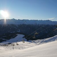 Schneebedeckte Berge und Seilbahnen im Winterlicht.