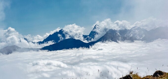 Majestueuze bergen stijgen boven een wolkenbedekking.