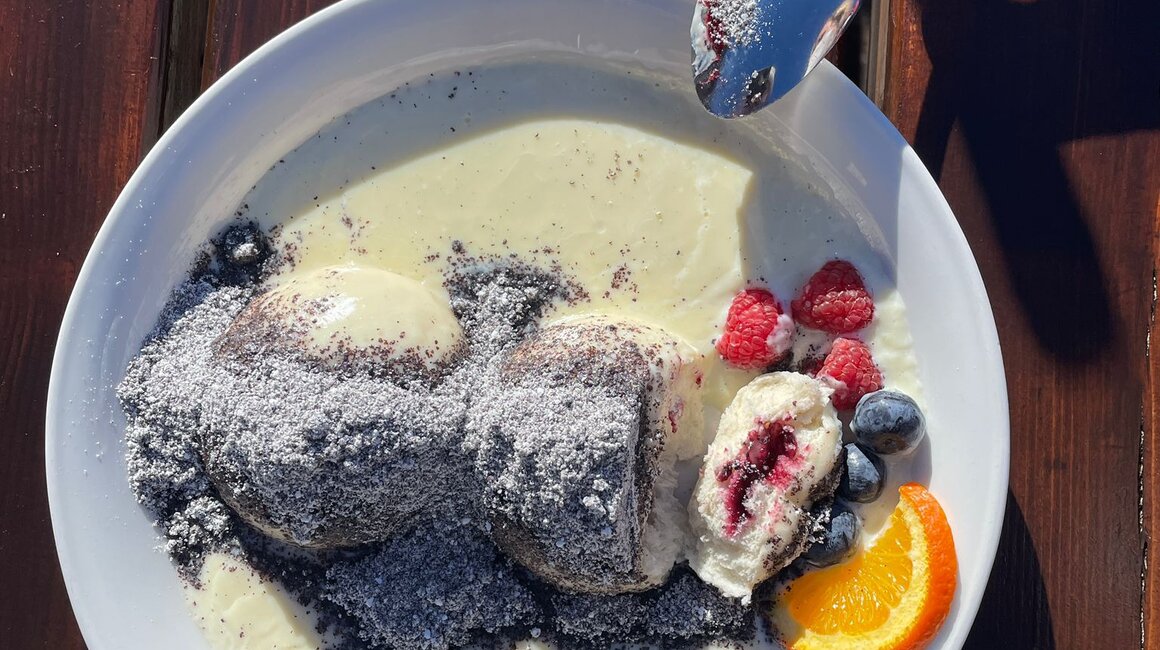 Zwei Schokoladenkugeln mit Sahnesoße, Beeren und Orange.