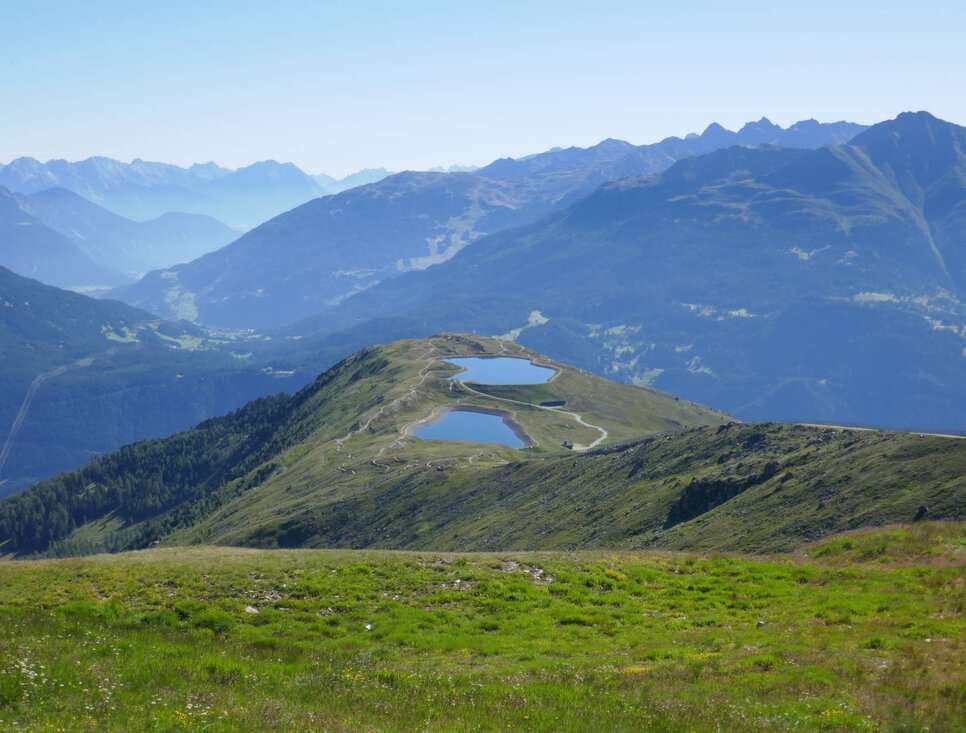 Blick auf eine Gebirgslandschaft mit zwei Wasserbecken von oben.