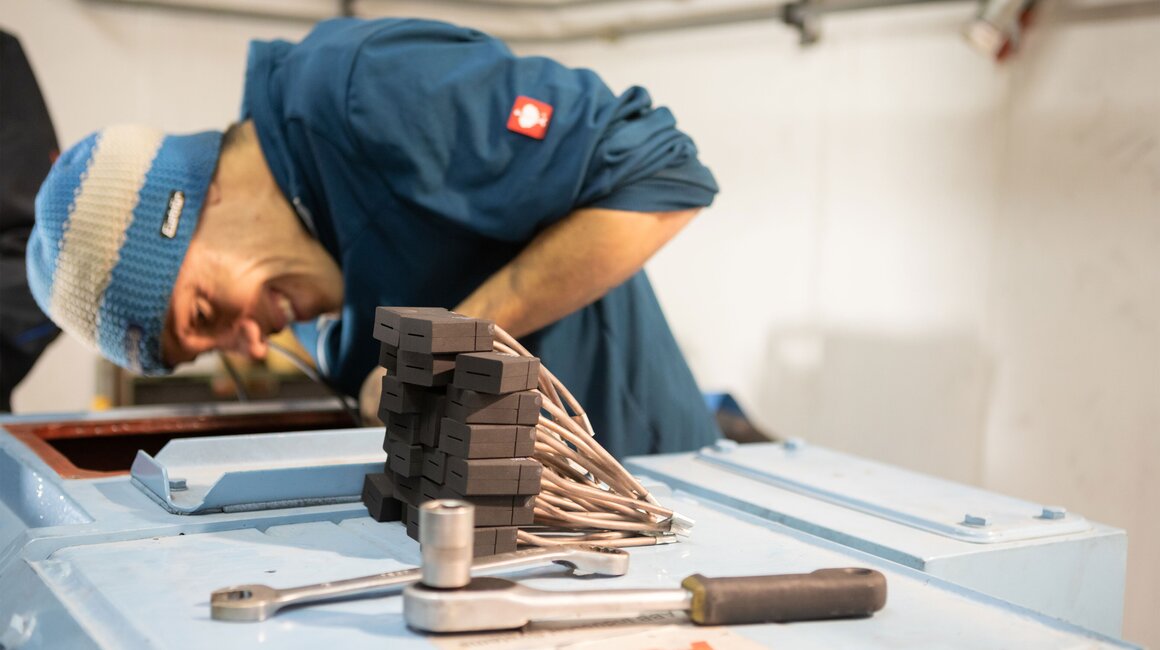Ein Techniker arbeitet an einer Maschine, mit Werkzeug und Kabeln.