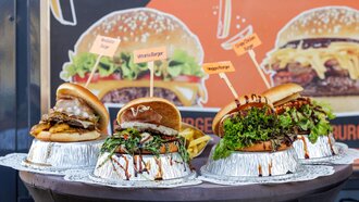 Vier verschiedene Burger mit Beschriftung auf einem Tisch.