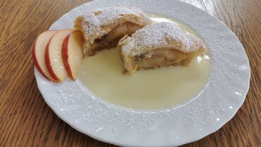Zwei Stücke Apfelstrudel auf einem Teller mit Vanillesoße.