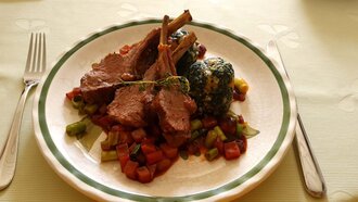 Ein Teller mit Lamm, Gemüse und Spinatbällchen.