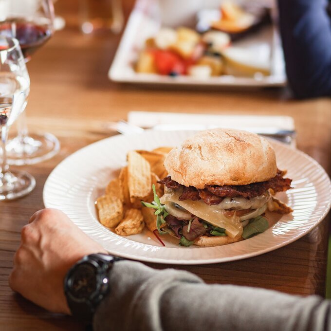 Saftiger Burger mit Salat und Kartoffeln, serviert mit Wein.