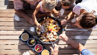 Familie genießt ein großzügiges Gericht im Freien.