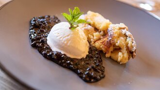 Ein Dessert mit Vanilleeis und einer fruchtigen Sauce auf einem Teller.