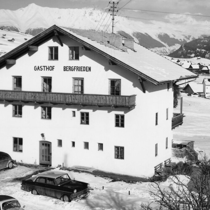 Ein gasthof in winterlicher Landschaft mit Schnee und Bergen.