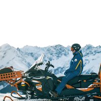 Ein Schneemobil-Fahrer blickt auf die verschneiten Berge.