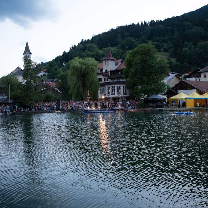 Gemütliche Atmosphäre am See mit Menschen und Festzelten.