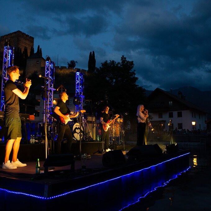 Band spielt bei Nacht mit beleuchtetem Bühnensetup.