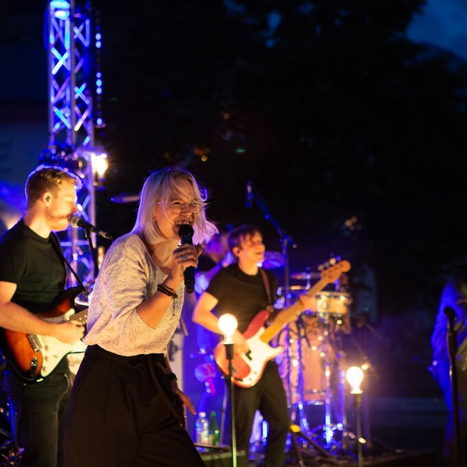 Eine Band spielt live bei Nacht, das Publikum genießt die Musik.