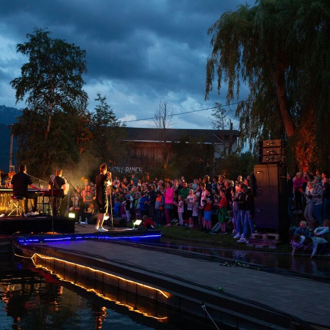 Konzert am Abend mit einer Menge von Zuschauern am Wasser.