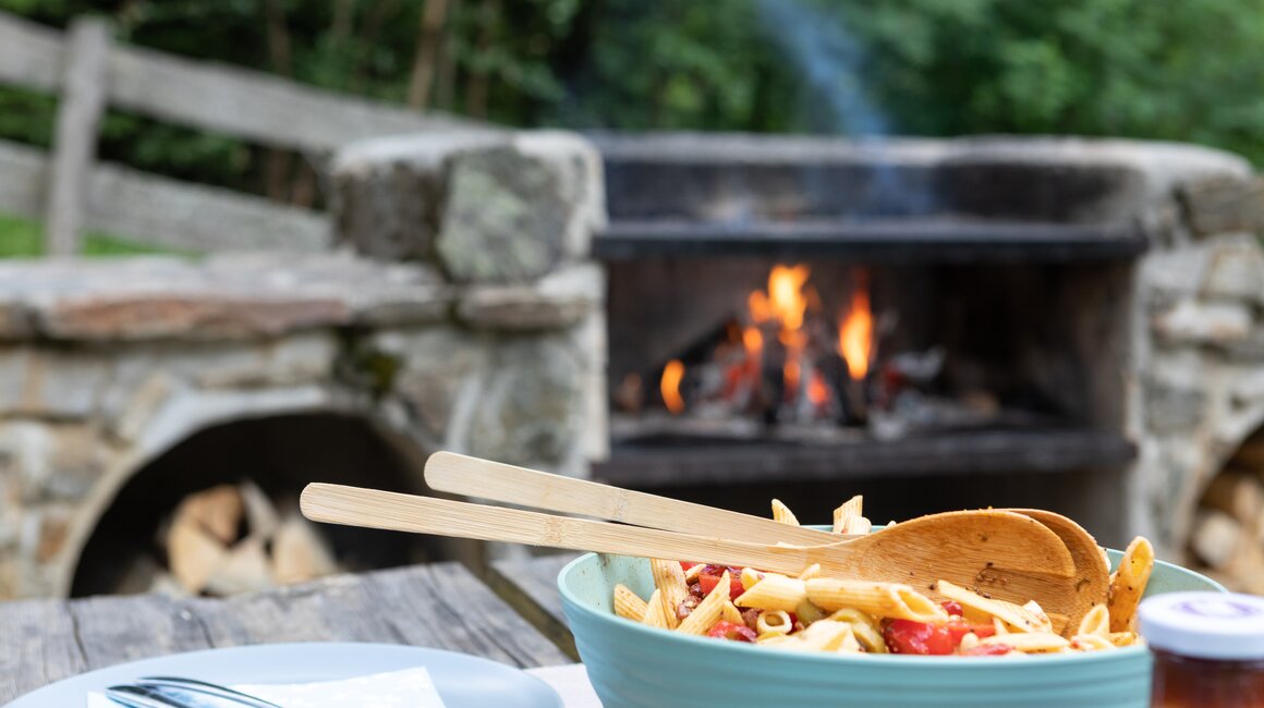 Ein buntes Pasta-Gericht mit einem Lagerfeuer im Hintergrund.