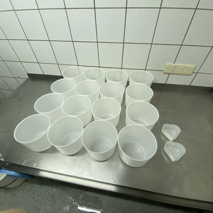 Mehrere weiße Behälter auf einem Tisch in einer gefliesten Umgebung.