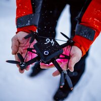 Eine Person präsentiert eine Drohne, während es schneit.
