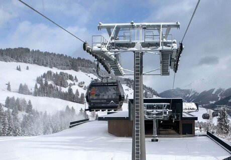 A cable car travels over snowy mountains.